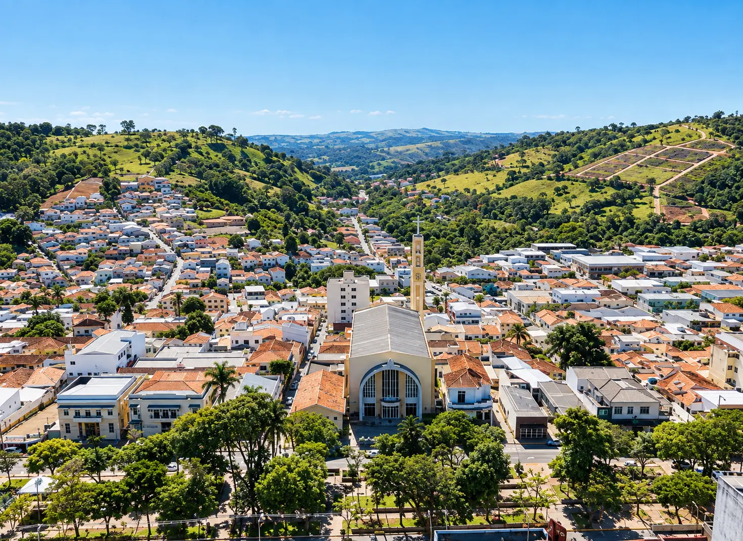 Vista aérea de uma cidade mineira com igreja de torre sineira entre colinas verdes
